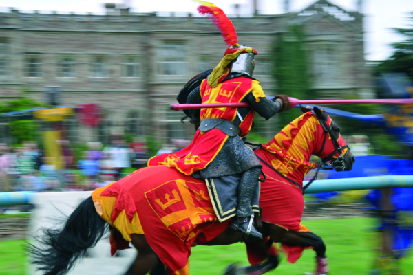 A knight in mail and red tabards jousting.