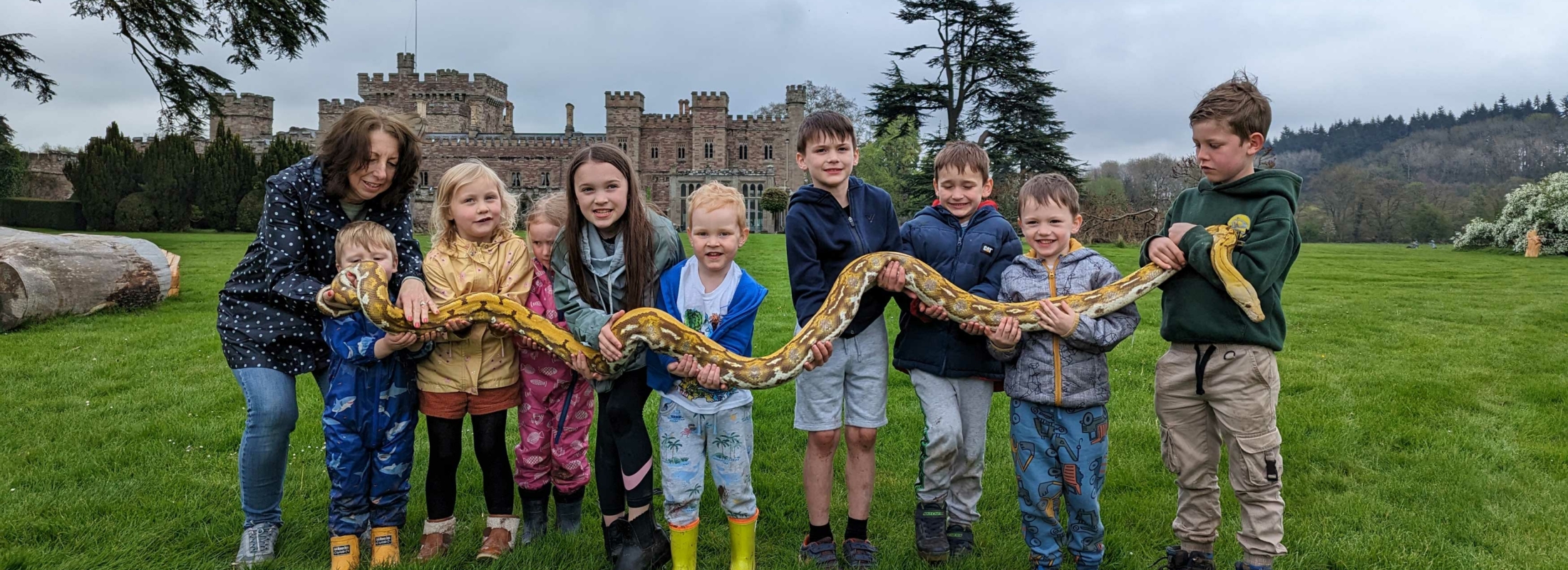 Children holding a snake during a fun day out at Hampton Gardens
