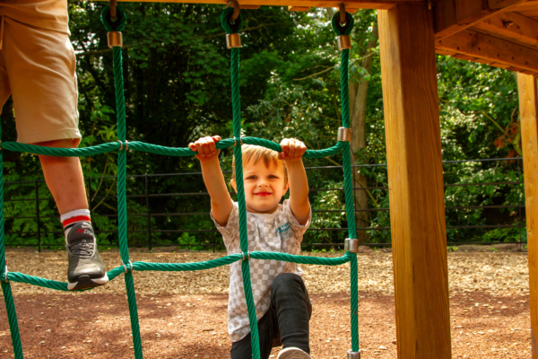 Child climbing a scramble net on the play area