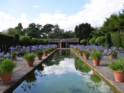 Long reflective canal of water with agapanthus in pots around the edges