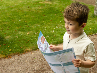 child-holding-trail-guide-whilst-walking-along-path